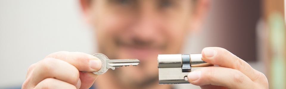 Man holding a house key next to a euro lock cylinder