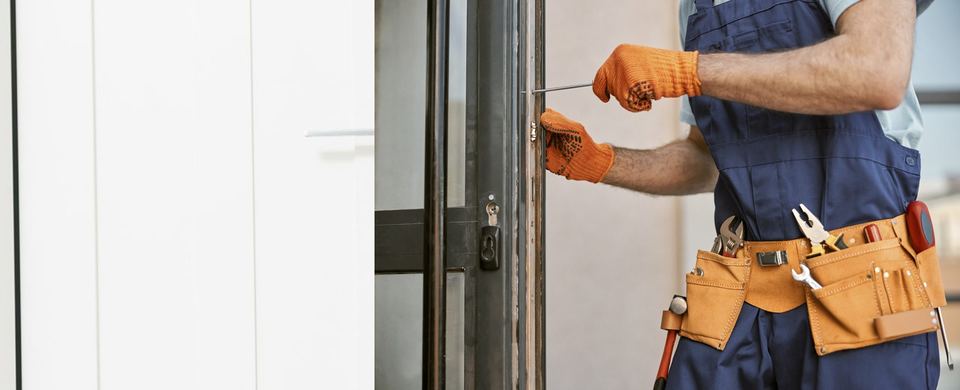 Locksmith with a tool belt fitting a lock into the edge of a door