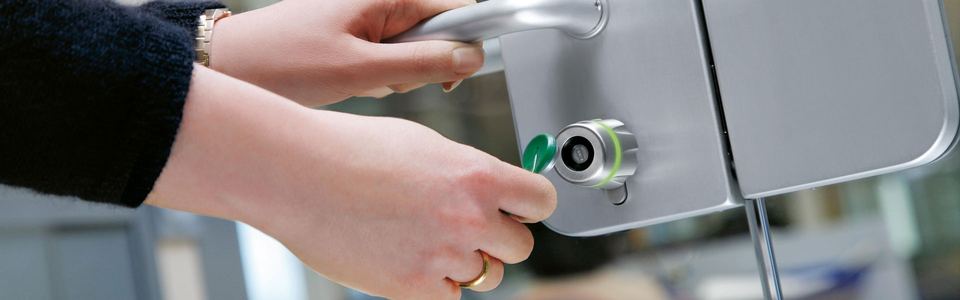 Hand turning a key in the lock of a glass office door